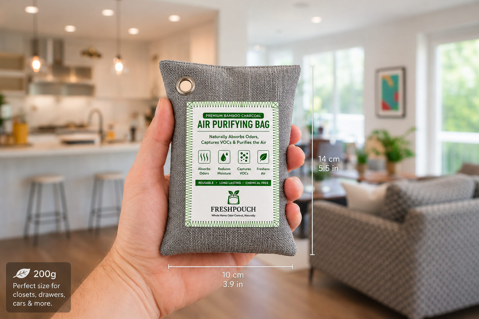 A hand holds a small gray air purifying sachet with a white and green label reading Freshpouch. The background shows a blurred modern living room and kitchen.