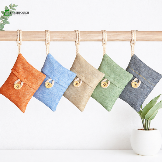 Five colorful fabric pouches with buttons hanging on a bamboo rod against a white background.