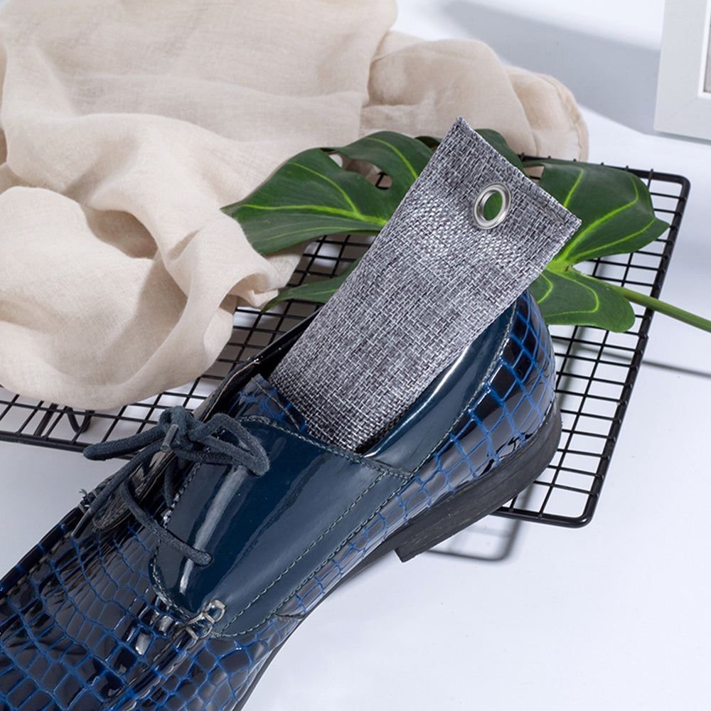 Blue shoe with a gray sock on a white surface with green leaves