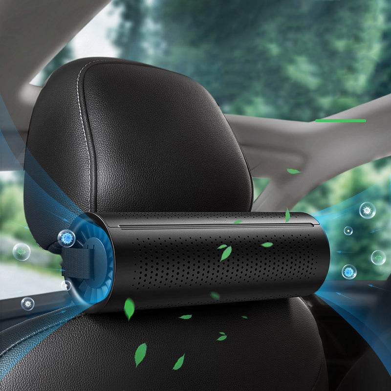 Car air freshener attached to a car headrest with a blurred green outdoor background